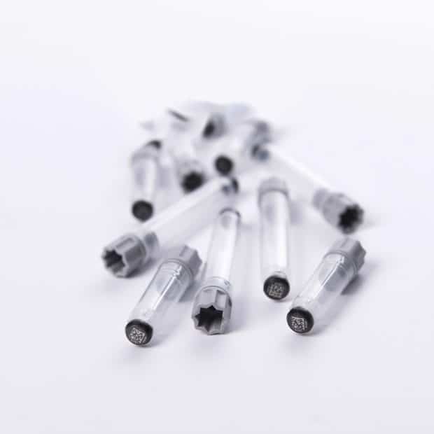 A pile of externally threaded tubes precapped with grey screw caps